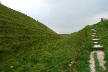 The scale of these earth banks can be seen from the two people walking along the top of the innermost bank while I am standing in the ditch below it.