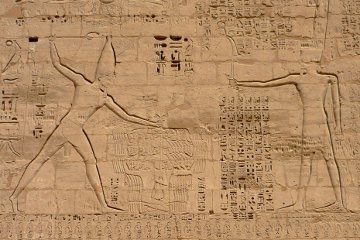 In this relief from Medinet Habu Rameses III stands before Amun. He is about to club to death the group of prisoners he is holding by the hair.